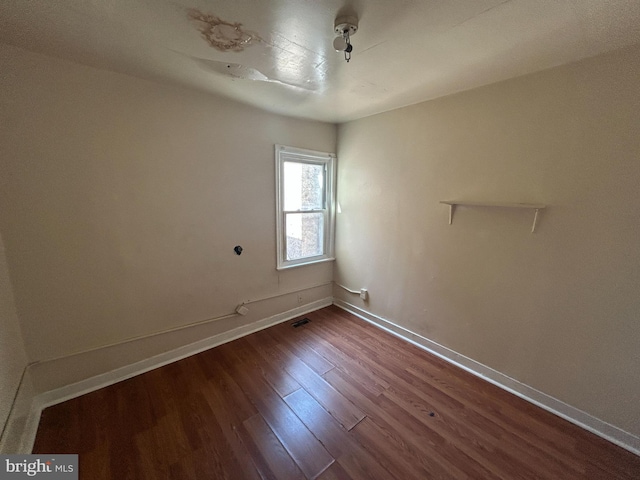 unfurnished room with dark wood-type flooring and baseboards