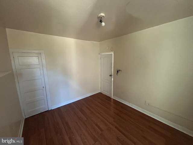 spare room featuring dark wood-style floors and baseboards