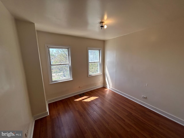 empty room featuring dark wood-style floors and baseboards