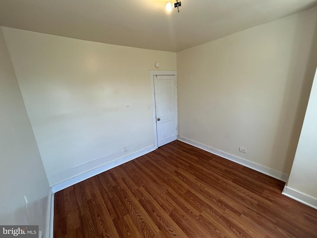 unfurnished room featuring baseboards and dark wood-style flooring