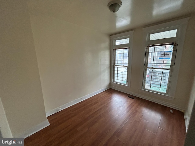 unfurnished room with dark wood-type flooring and baseboards
