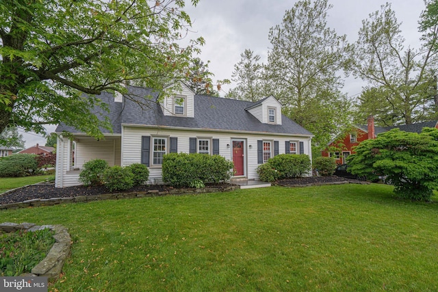 new england style home with a front yard and a shingled roof