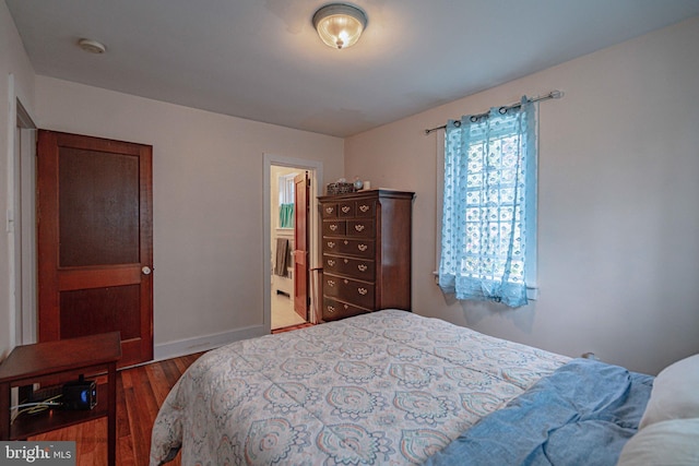 bedroom with wood finished floors, baseboards, and ensuite bathroom