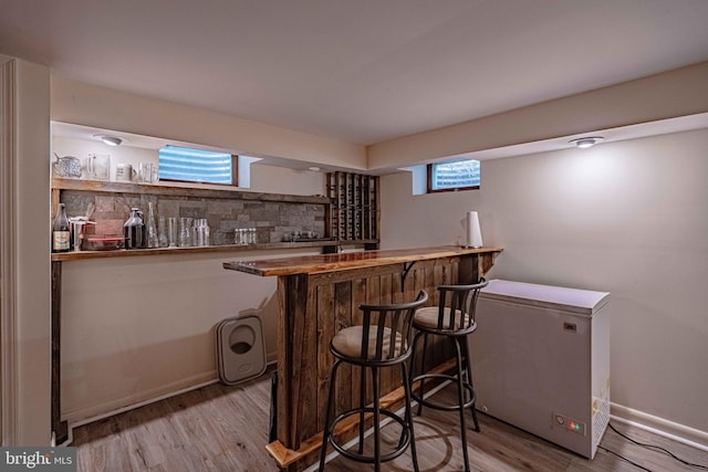 indoor dry bar featuring wood finished floors, fridge, and baseboards