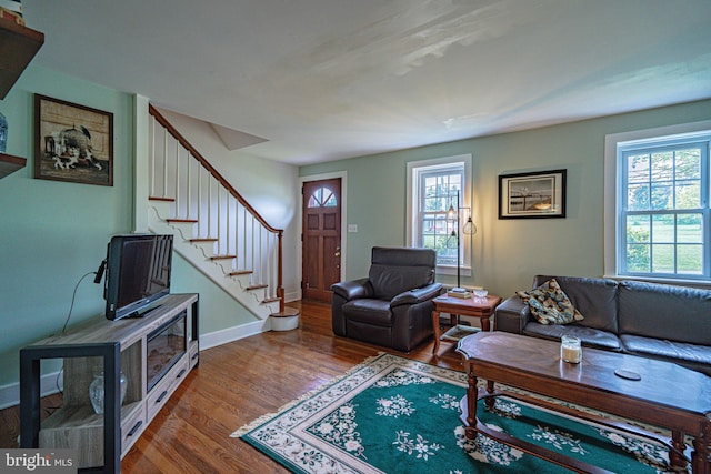 living room with wood finished floors, stairs, and baseboards