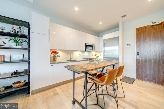 45 Sutton Sq SW Unit Ph11, Washington, DC 20024 - kitchen with appliances with stainless steel finishes, a sink, light wood-style flooring, white cabinets, and recessed lighting