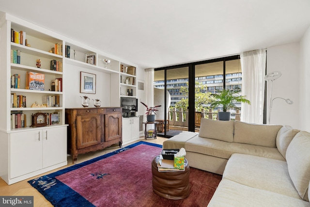 living room with light wood-style flooring, built in features, and expansive windows