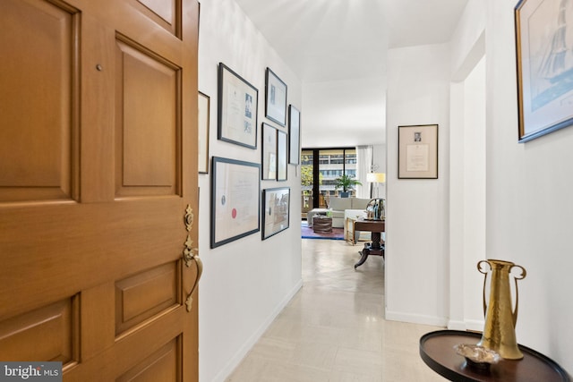 hall featuring baseboards and light flooring