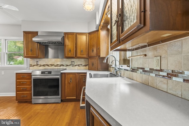 15 Renee, Lawrence Township, NJ 08648 - kitchen with stainless steel range with electric stovetop, wall chimney range hood, a sink, brown cabinetry, and tasteful backsplash