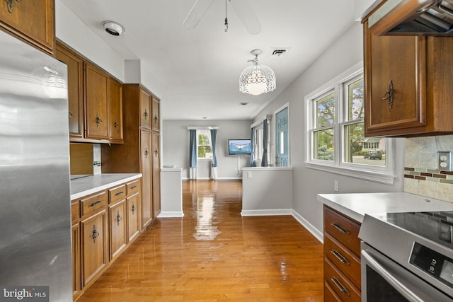 15 Renee, Lawrence Township, NJ 08648 - kitchen with stainless steel refrigerator, light countertops, light wood-type flooring, decorative backsplash, and brown cabinets
