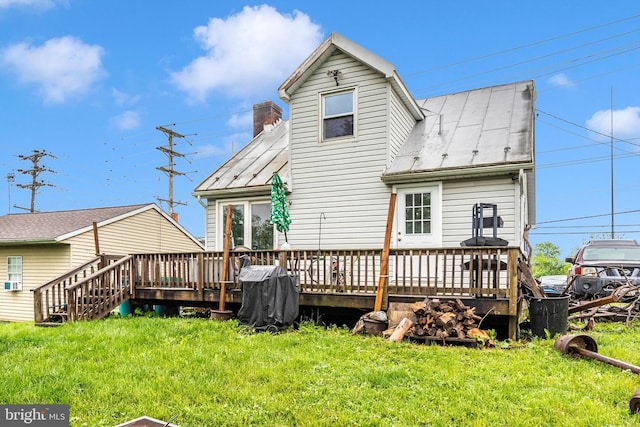 back of property with a wooden deck, a yard, and a chimney