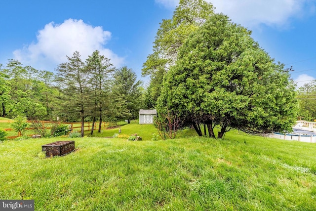 view of grassy yard featuring a storage unit, an outdoor structure, and a fire pit