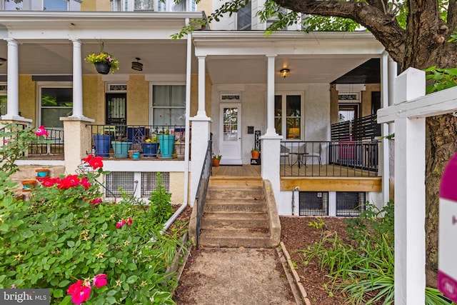 doorway to property featuring a porch and stucco siding