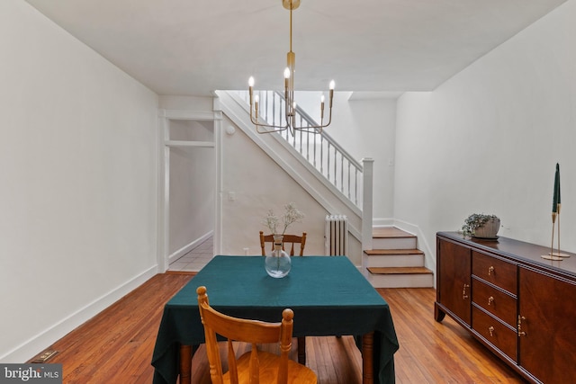dining room with light wood-style floors, radiator heating unit, stairway, and baseboards