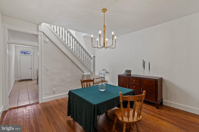 dining area featuring hardwood / wood-style floors, baseboards, a chandelier, and stairs