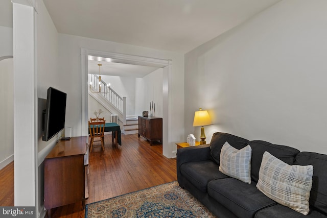 living room with hardwood / wood-style floors, stairs, a chandelier, and baseboards