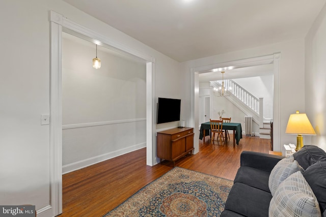 living room with wood finished floors, a chandelier, radiator, stairs, and baseboards