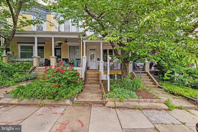 view of front facade featuring a porch, stucco siding, and stairs