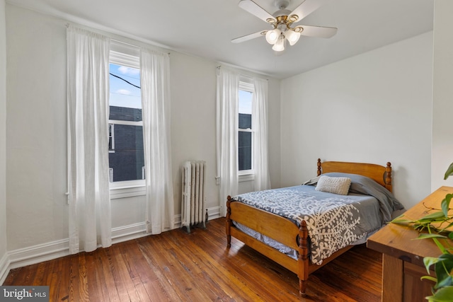 bedroom with radiator heating unit, hardwood / wood-style flooring, baseboards, and ceiling fan
