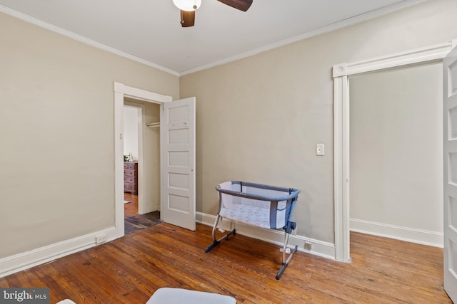 interior space with ornamental molding, wood finished floors, baseboards, and a ceiling fan