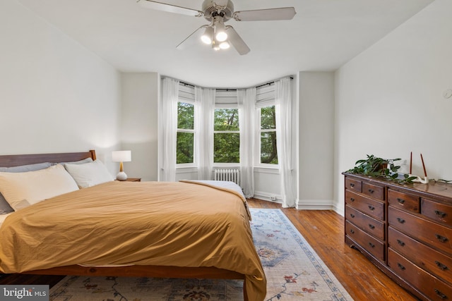 bedroom featuring baseboards, wood finished floors, and a ceiling fan