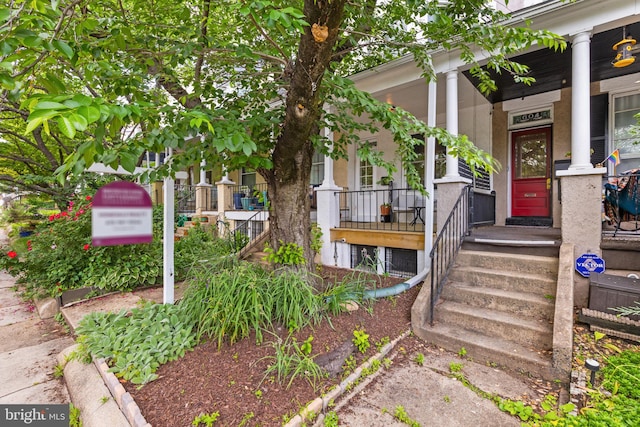 entrance to property featuring a porch and stucco siding