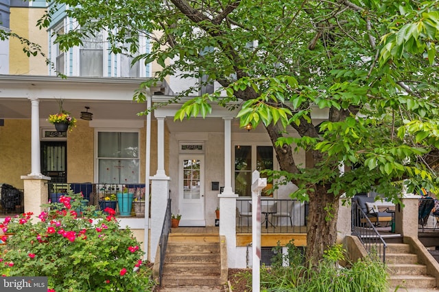 entrance to property with covered porch and stucco siding
