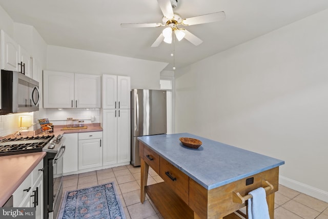 kitchen with stainless steel appliances, ceiling fan, light tile patterned flooring, and white cabinets