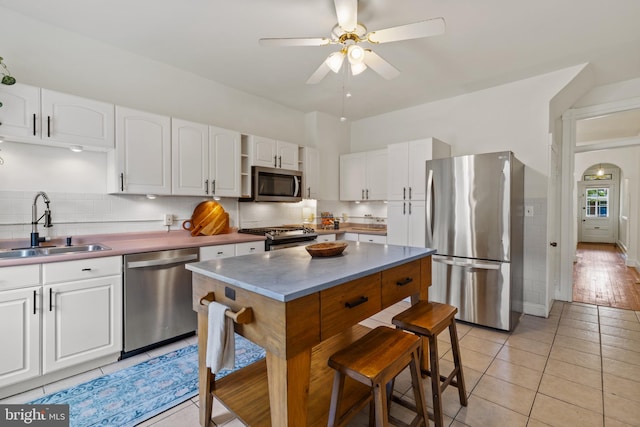 kitchen featuring stainless steel appliances, a sink, a ceiling fan, and white cabinetry