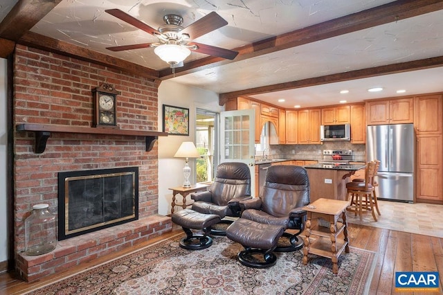 living room featuring light wood-style flooring, beam ceiling, ceiling fan, a brick fireplace, and recessed lighting