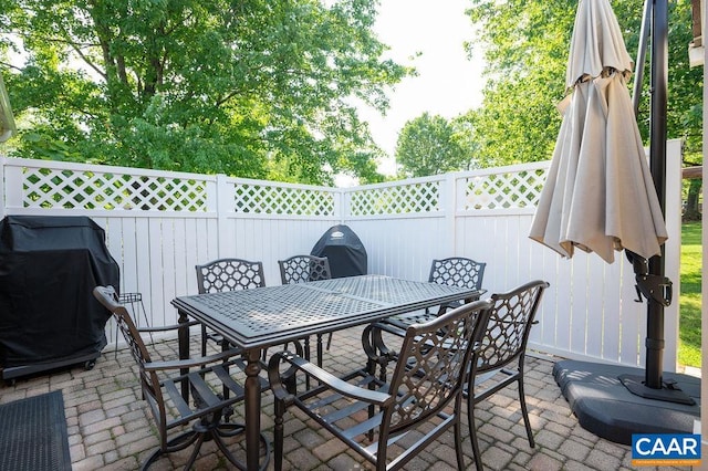 view of patio with fence, outdoor dining space, and a grill