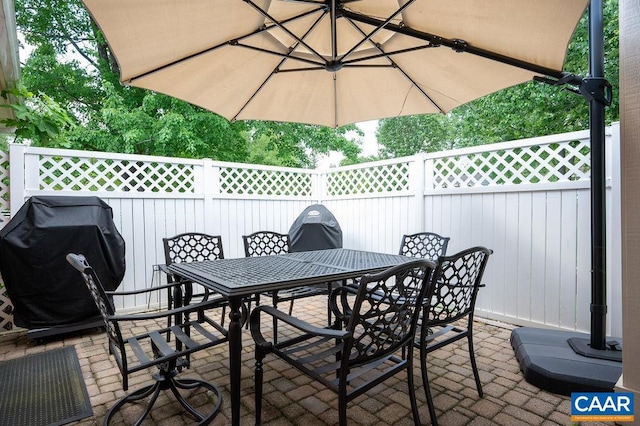 view of patio with outdoor dining area, fence, and grilling area