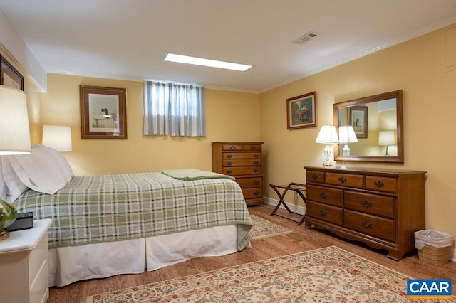 bedroom featuring wood finished floors, crown molding, and baseboards