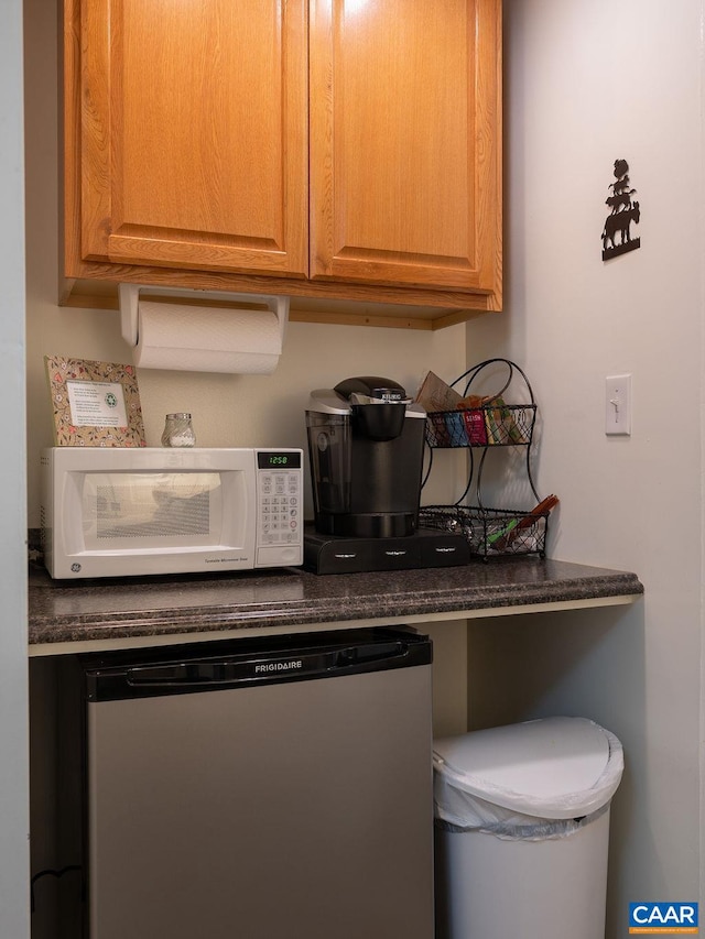 kitchen with white microwave, dishwashing machine, and dark countertops