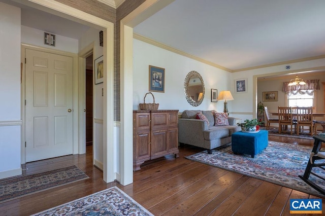 living area featuring hardwood / wood-style flooring, ornamental molding, and a chandelier