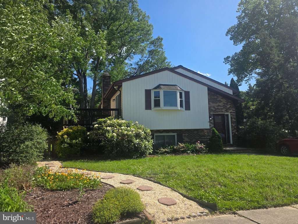view of front of house with a chimney, a front yard, and brick siding