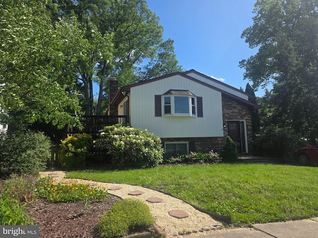 view of front of house with a chimney, a front yard, and brick siding