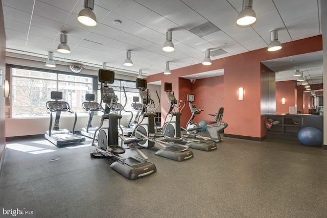 exercise room with baseboards and a drop ceiling
