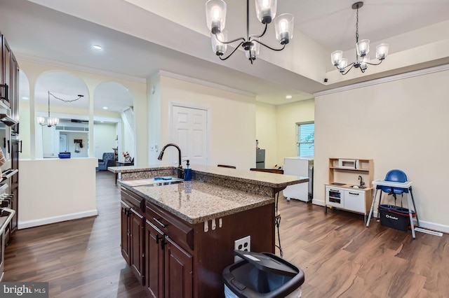 5622 Pilgrim Rd, Baltimore, MD 21214 - kitchen with a chandelier, a kitchen breakfast bar, dark wood-style floors, light stone countertops, and an island with sink