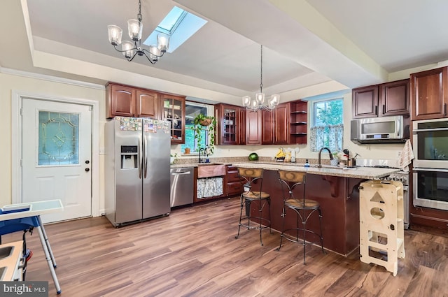 5622 Pilgrim Rd, Baltimore, MD 21214 - kitchen featuring stainless steel appliances, a tray ceiling, a chandelier, light wood-style floors, and a breakfast bar area