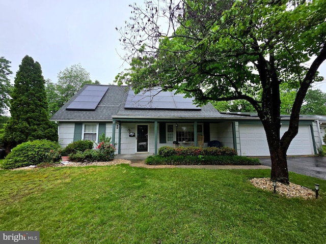 view of front of property with a front lawn, a shingled roof, roof mounted solar panels, and an attached garage