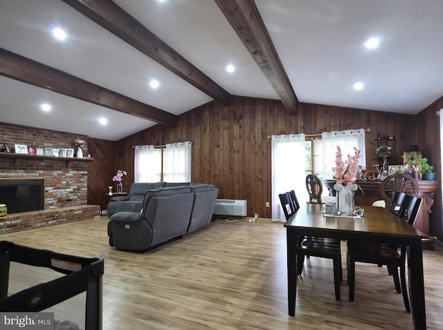 dining area featuring wood walls, wood finished floors, a wall unit AC, and a brick fireplace