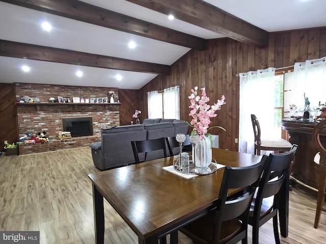dining space featuring wood walls, wood finished floors, and a fireplace