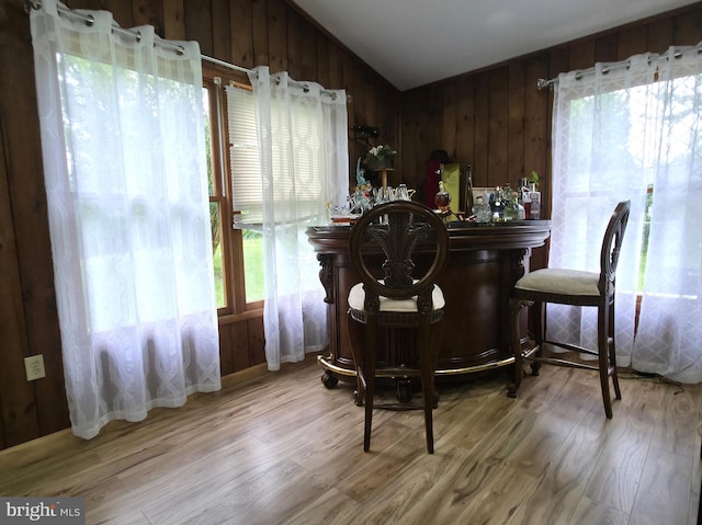 indoor dry bar with wood finished floors, vaulted ceiling, plenty of natural light, and wooden walls
