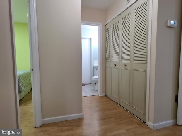 corridor with light wood finished floors and baseboards