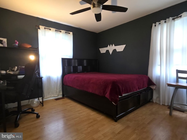 bedroom featuring multiple windows, wood finished floors, and a ceiling fan