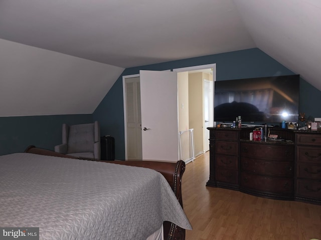 bedroom with vaulted ceiling, light wood-type flooring, and a closet