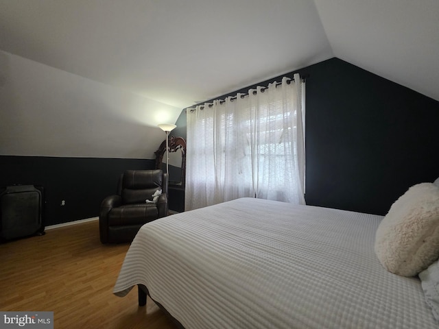 bedroom with lofted ceiling, wood finished floors, and baseboards