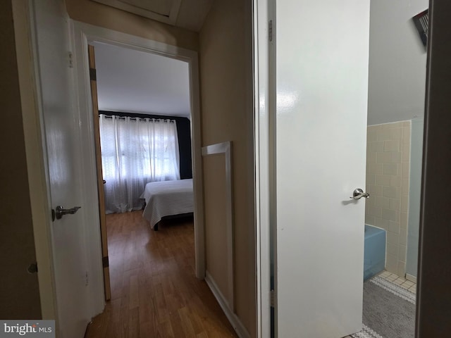 hall featuring wood finished floors and tile walls