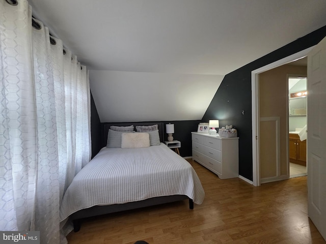 bedroom featuring light wood-style floors, lofted ceiling, and baseboards